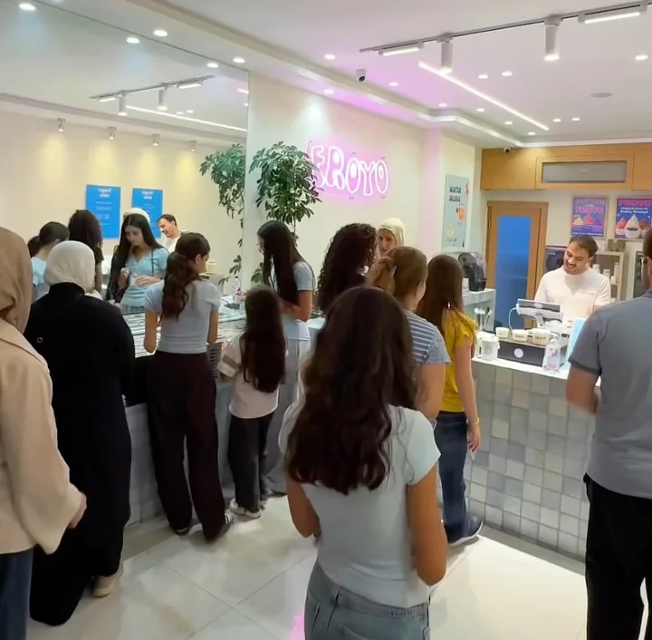 زباين على كاونتر فرويو المبلّط تحت لوحة النيون الزهري